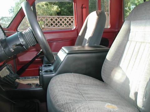 1990 Ford F-250 - The interior of a truck shows the driver's seat, passenger seat, and center console with cup holders.