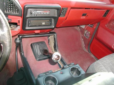1990 Ford F-250 - The interior of a 1990 Ford F-250 shows a red dashboard, a floor-mounted gear shifter, and an aftermarket radio.