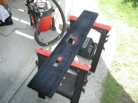 1990 Ford F-250 - A detached vehicle console part is cleaned with a shop vac outdoors.