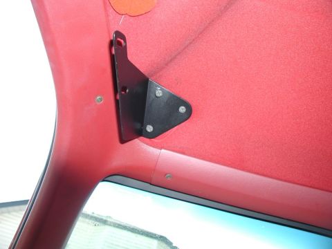 1990 Ford F-250 - A black metal bracket is attached to the red headliner of a vehicle's interior, likely for an overhead console.
