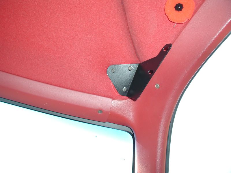 Black metal bracket attached to red interior headliner near windshield