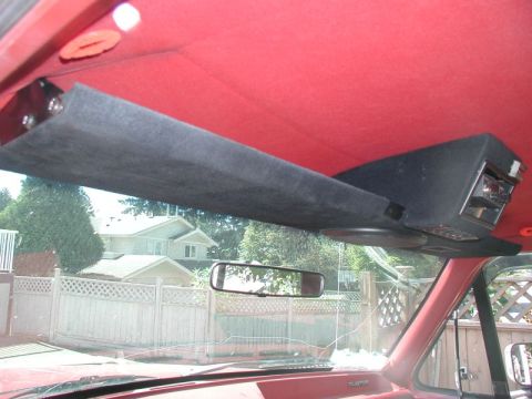 1990 Ford F-250 - The custom overhead console in the vehicle houses a radio and speakers, with a view of the outside through the windshield.
