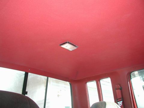 1990 Ford F-250 - The interior of a vehicle shows a red headliner with a central dome light and windows.