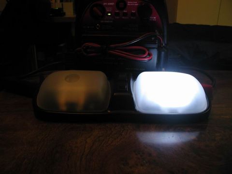 1990 Ford F-250 - A battery charger is connected to two vehicle dome lights, one of which is illuminated.