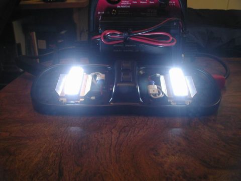 1990 Ford F-250 - A domelight assembly with LED bulbs and a switch is connected to a battery charger on a wooden surface.