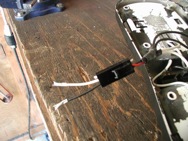 Domelight wiring with a black connector and exposed wires on a wooden surface