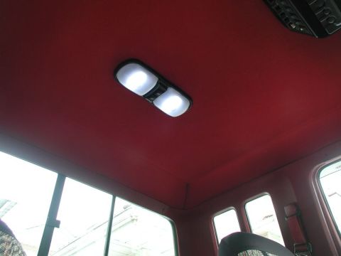 1990 Ford F-250 - Interior view of a vehicle's red headliner with illuminated dome lights and a visible overhead console.