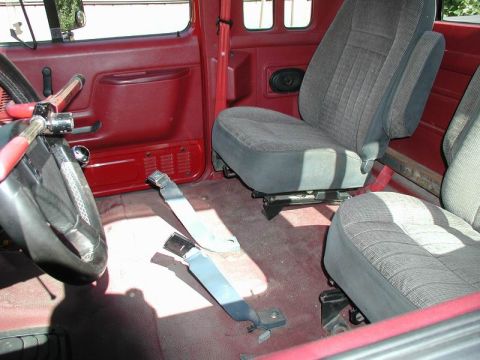 1990 Ford F-250 - The interior of a truck shows red door panels and gray fabric seats with seatbelts lying on the floor.