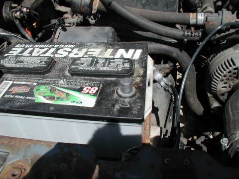 1990 Ford F-250 - Close-up view of an engine bay, focusing on the Interstate Mega-Tron Plus battery and surrounding components like hoses and the alternator.