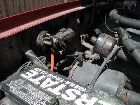 1990 Ford F-250 - Close-up view of the starter relay and battery in the engine compartment.