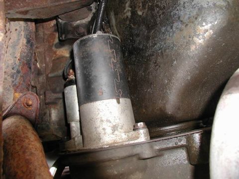 1990 Ford F-250 - Close-up view of a starter motor and surrounding engine components, showing signs of rust and wear.