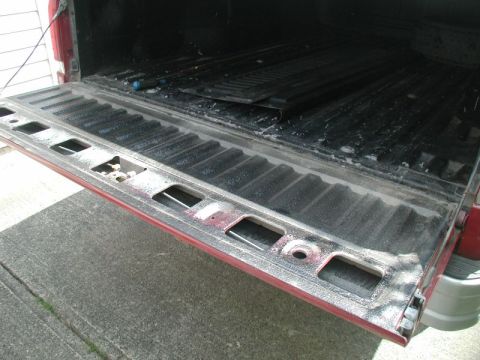 1990 Ford F-250 - The rear of a red pickup truck, focusing on the open tailgate and bed interior.
