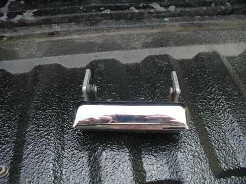 1990 Ford F-250 - Close-up of a chrome tailgate handle on a textured black truck bed.