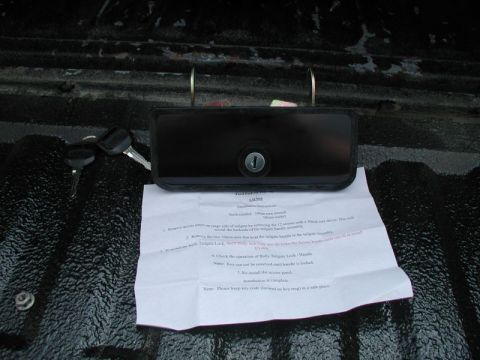 1990 Ford F-250 - A new tailgate lock assembly and keys are shown with installation instructions on a truck bed.