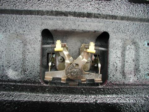 1990 Ford F-250 - Close-up view of a tailgate lock mechanism, metal components and yellow plastic clips.