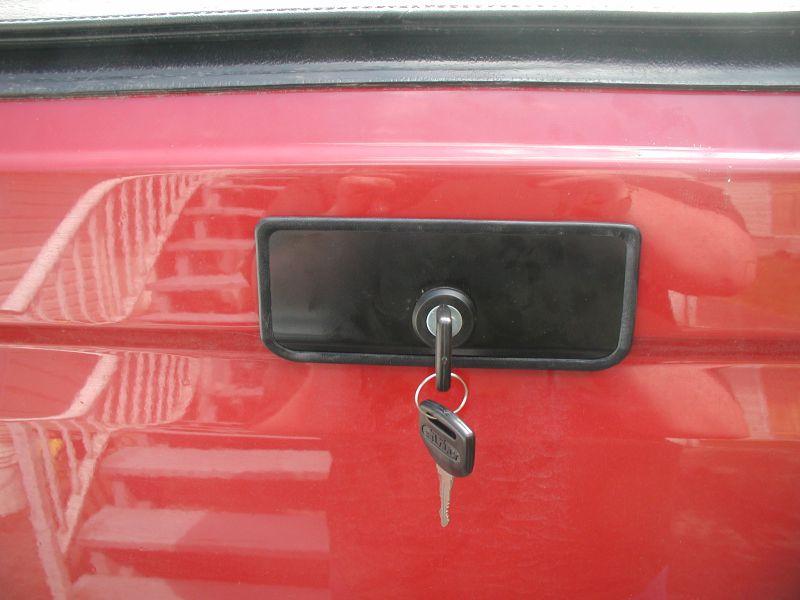 Red tailgate with black lock and keys. Text 'SUPERMOTORS' visible