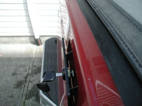 1990 Ford F-250 - Close-up of a red truck's tailgate lock mechanism with a key in place.