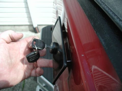 1990 Ford F-250 - A hand is shown inserting a key into the tailgate lock mechanism of a red 1990 Ford F-250 pickup truck.
