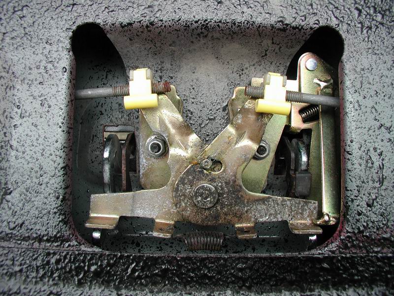 Close-up of a truck tailgate or door latch mechanism with yellow plastic clips