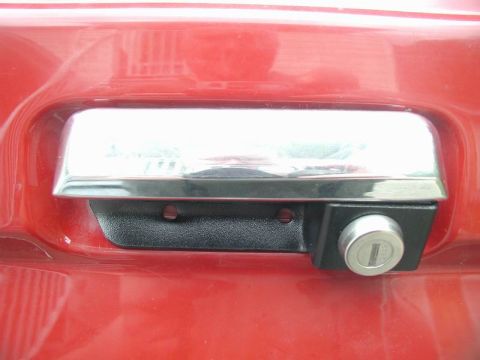 1990 Ford F-250 - Tailgate lock assembly on a red vehicle, showing the chrome handle and key cylinder.