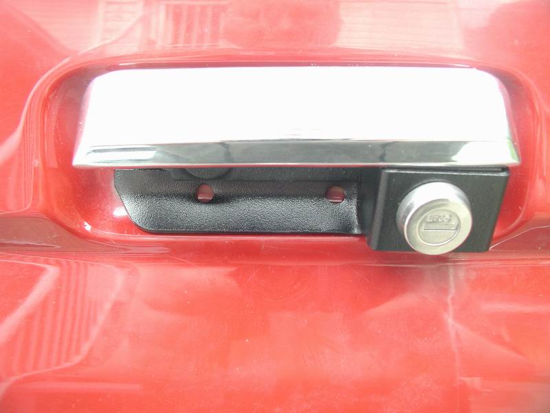 Close-up of a red vehicle's tailgate handle and lock cylinder