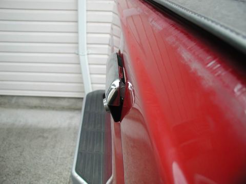 1990 Ford F-250 - Close-up of a red truck's tailgate lock mechanism, showing chrome accents.