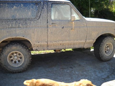 1990 Ford Bronco - This 1990 Ford Bronco is heavily covered in mud, obscuring its original paint and details.