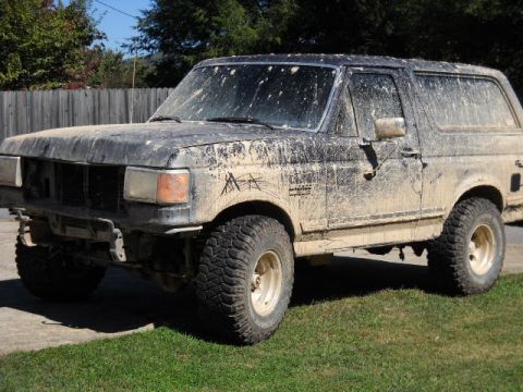 1990 Ford Bronco - This SUV is heavily coated in mud, obscuring much of its original appearance.