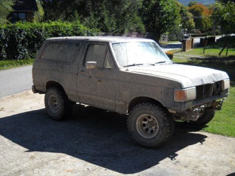 1990 Ford Bronco - This heavily soiled Ford Bronco, viewed from the front-right, appears to be from the late 1980s, not 1990.