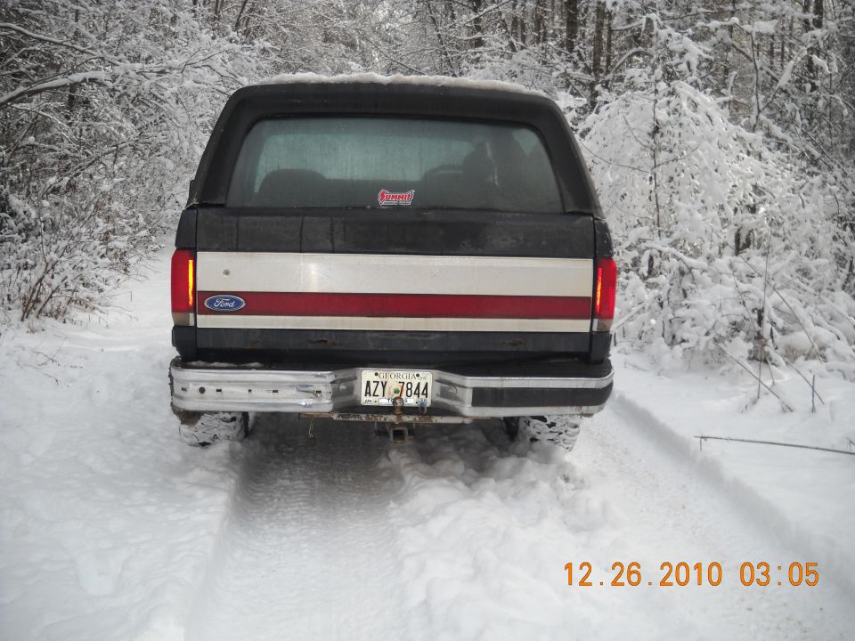 Rear view of black and white Ford Bronco in snow