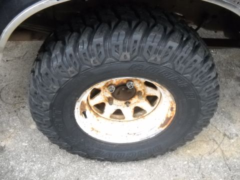 1990 Ford Bronco - A close-up view of a vehicle's tire and rusty wheel.