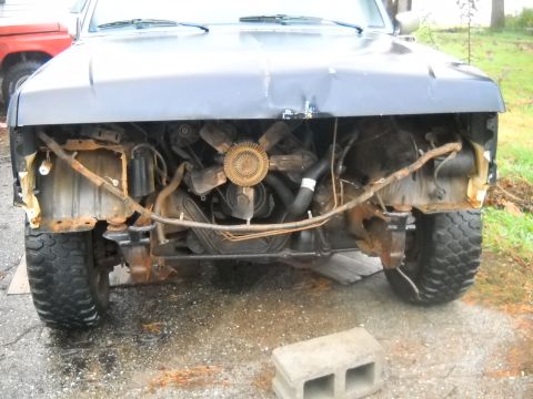 1990 Ford Bronco - The front of a vehicle is shown with its grille and bumper removed, exposing the engine and radiator.