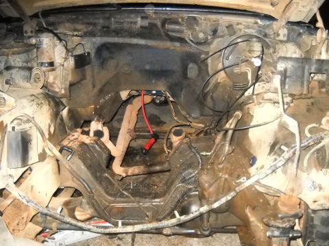 1990 Ford Bronco - The engine bay of a vehicle, showing the exhaust manifold and a red spark plug wire, with visible text from Supermotors.net.