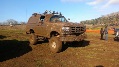 1995 Ford Bronco - Muddy 1995 Ford Bronco after off-roading event, with other vehicles in the background.