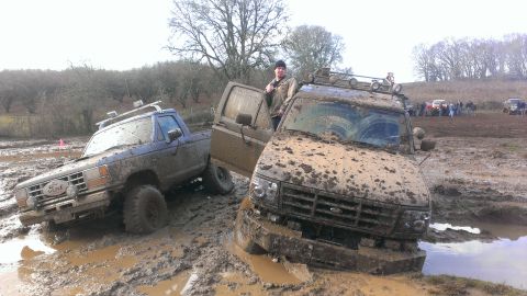 1995 Ford Bronco - Two Ford trucks are stuck in the mud during an off-road event.
