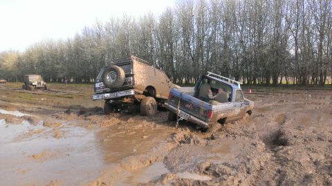 1995 Ford Bronco - Off-road vehicles struggle in thick mud during an event.