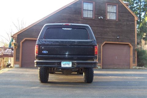 1996 Ford Bronco - This black 1996 Ford Bronco features a lifted suspension and is parked in front of a wooden house with a garage.