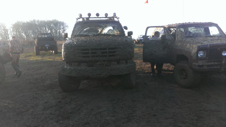 muddy trucks parked in a field, one with door open
