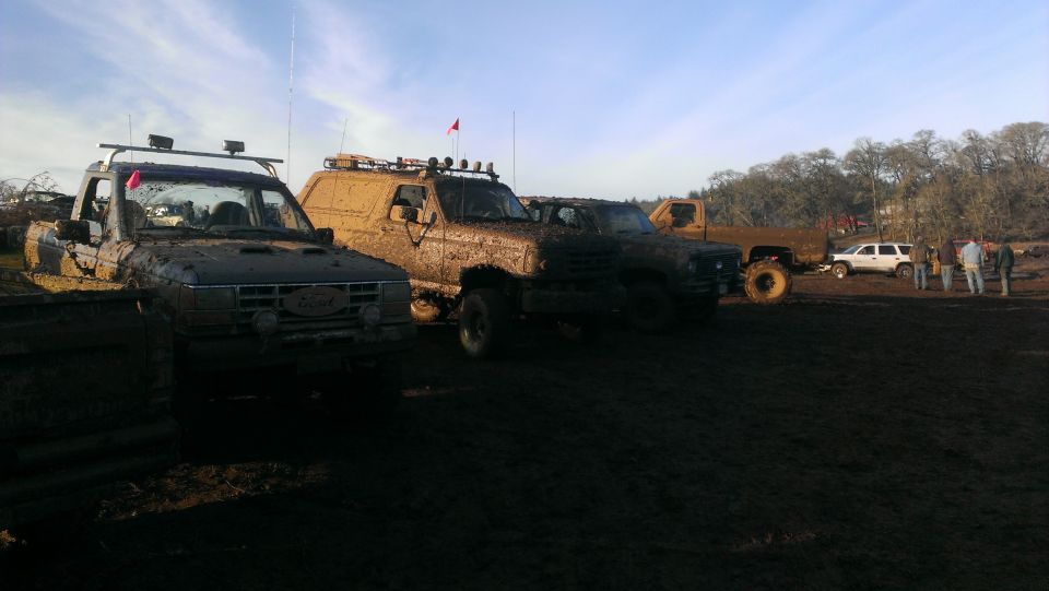 Muddy 1995 Ford Bronco and other off-road vehicles parked in mud