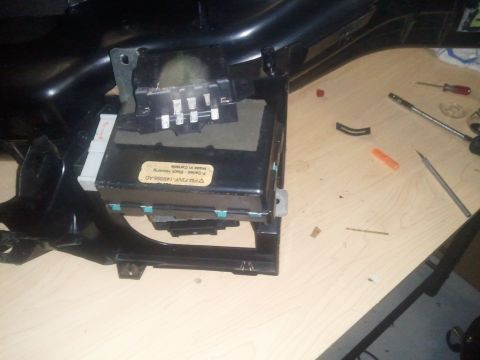 1994 Ford Bronco - A disassembled vehicle interior component is shown on a workbench with tools nearby.