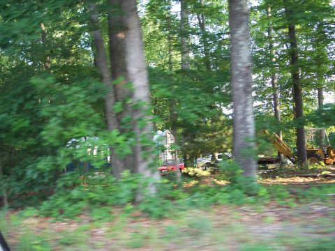 1971 Ford Ranchero - A red vehicle and construction equipment are visible amongst trees.