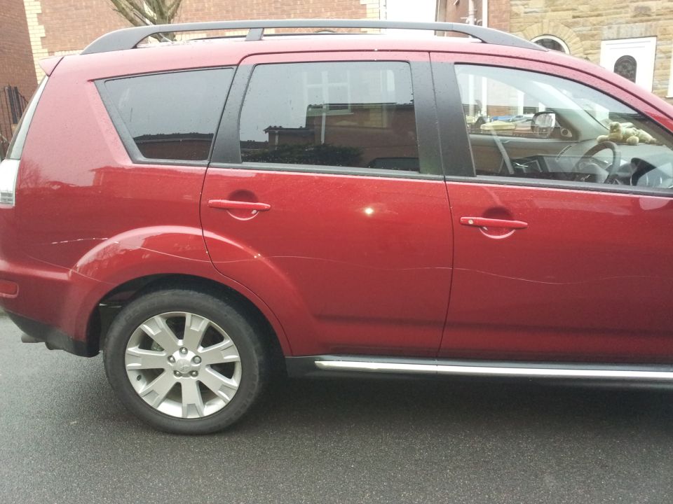 Maroon SUV rear-quarter side view showing alloy wheel and side step