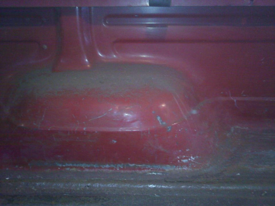 close-up of the red interior floor of a vehicle, showing some wear and tear