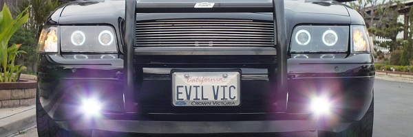 Cropped front of black Crown Victoria with halo lights billet grille EVIL VIC plate