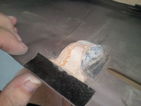 1994 Ford Bronco - Close-up of dashboard repair work in progress, with sandpaper being used on a textured surface.