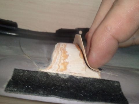 1994 Ford Bronco - A hand is shown sanding a piece of interior trim, likely for a dashboard repair.