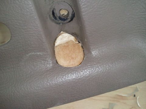 1994 Ford Bronco - Close-up of an interior trim panel with a hole cut into it, exposing the underlying wood structure.