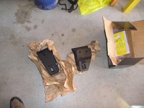 1997 Ford F-250 - Two black metal truck parts are shown, one unwrapped and one in its packaging, next to an open cardboard box with instructions.