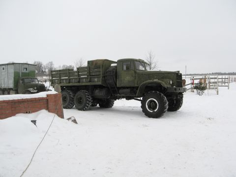 1987 Ford Bronco - A large green military truck with a flatbed and a trailer is parked in a snowy landscape.