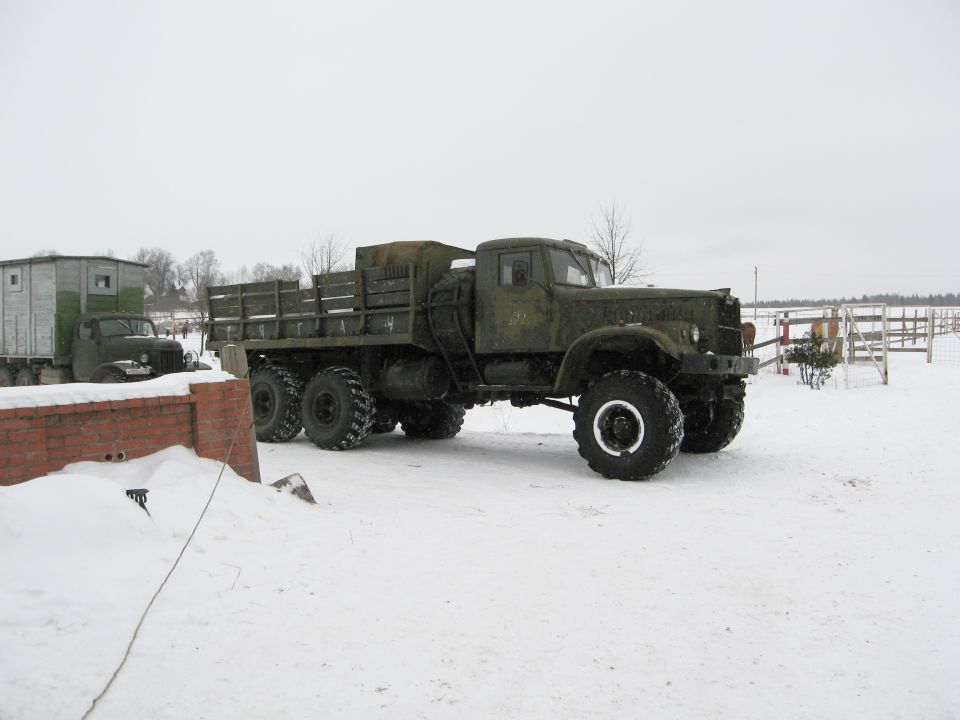 Green military truck with flatbed and trailer in snow